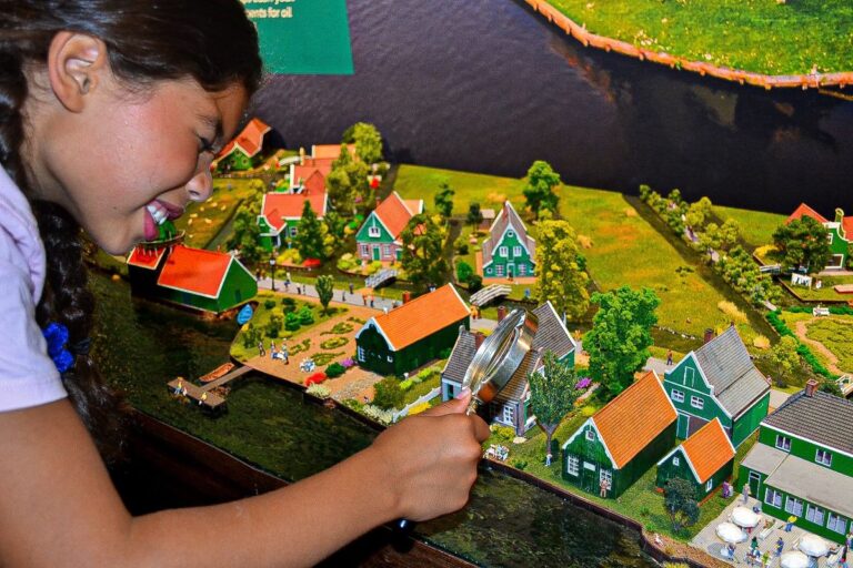 Meisje bekijkt de Zaanse Schans in miniatuur met een vergrootglas